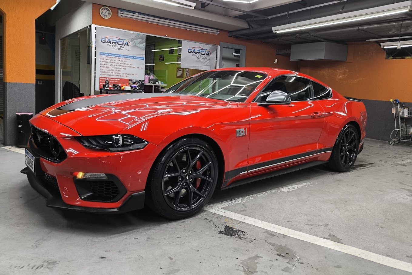 Ford Mustang Mach 1 vermelho na oficina da Garcia, sob o teto de LED hexagonal