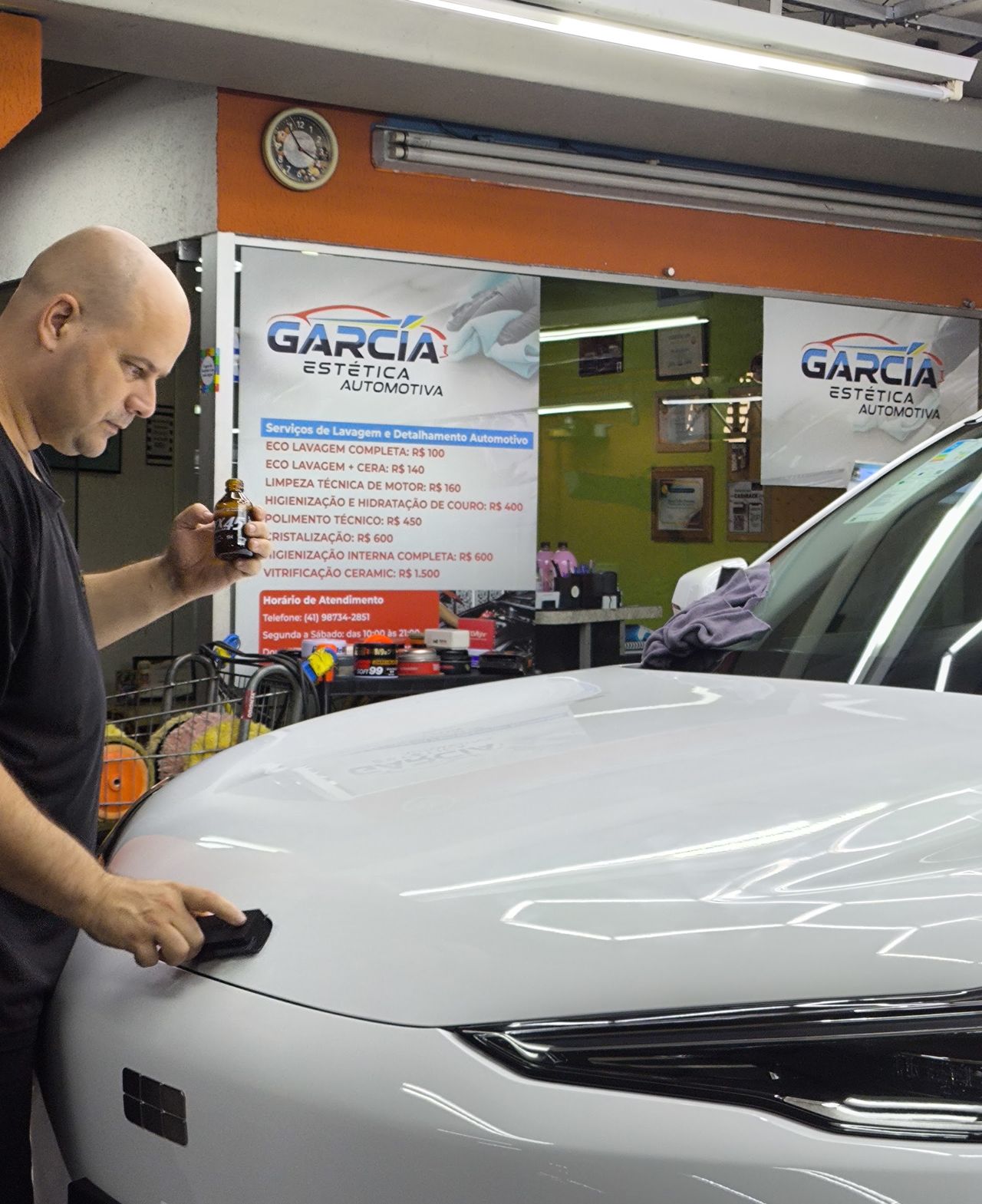 Profissional da Garcia ao lado de um carro branco, com o logo da empresa ao fundo