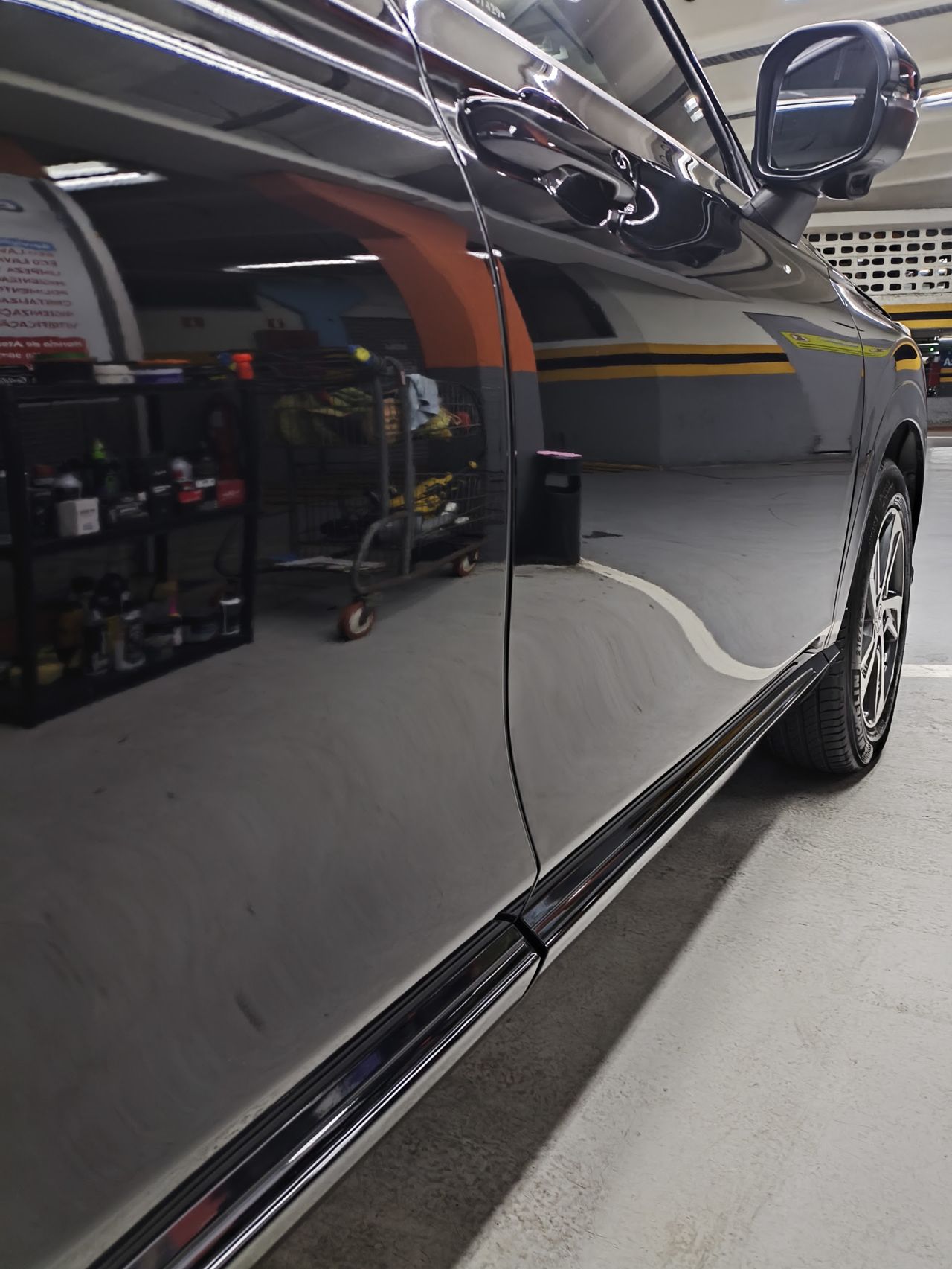 Lateral de carro escuro refletindo a oficina