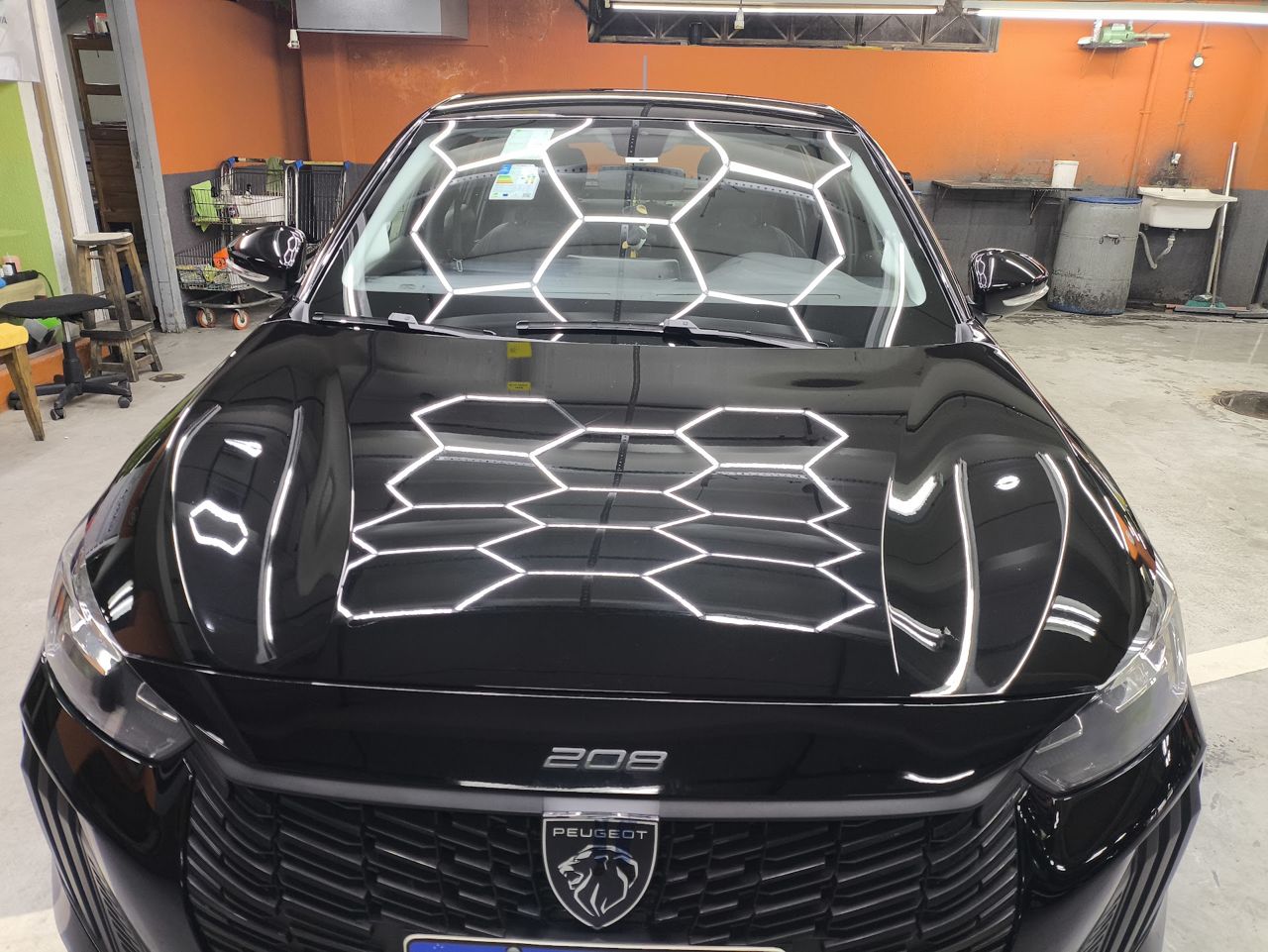 Capô preto de Peugeot 208 refletindo o teto de LED após o polimento